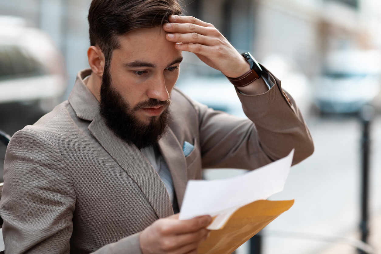 Frustrated person with hand on head reviewing a complex document from a manila envelope, symbolizing the hidden risks and challenges of using DIY legal forms.
