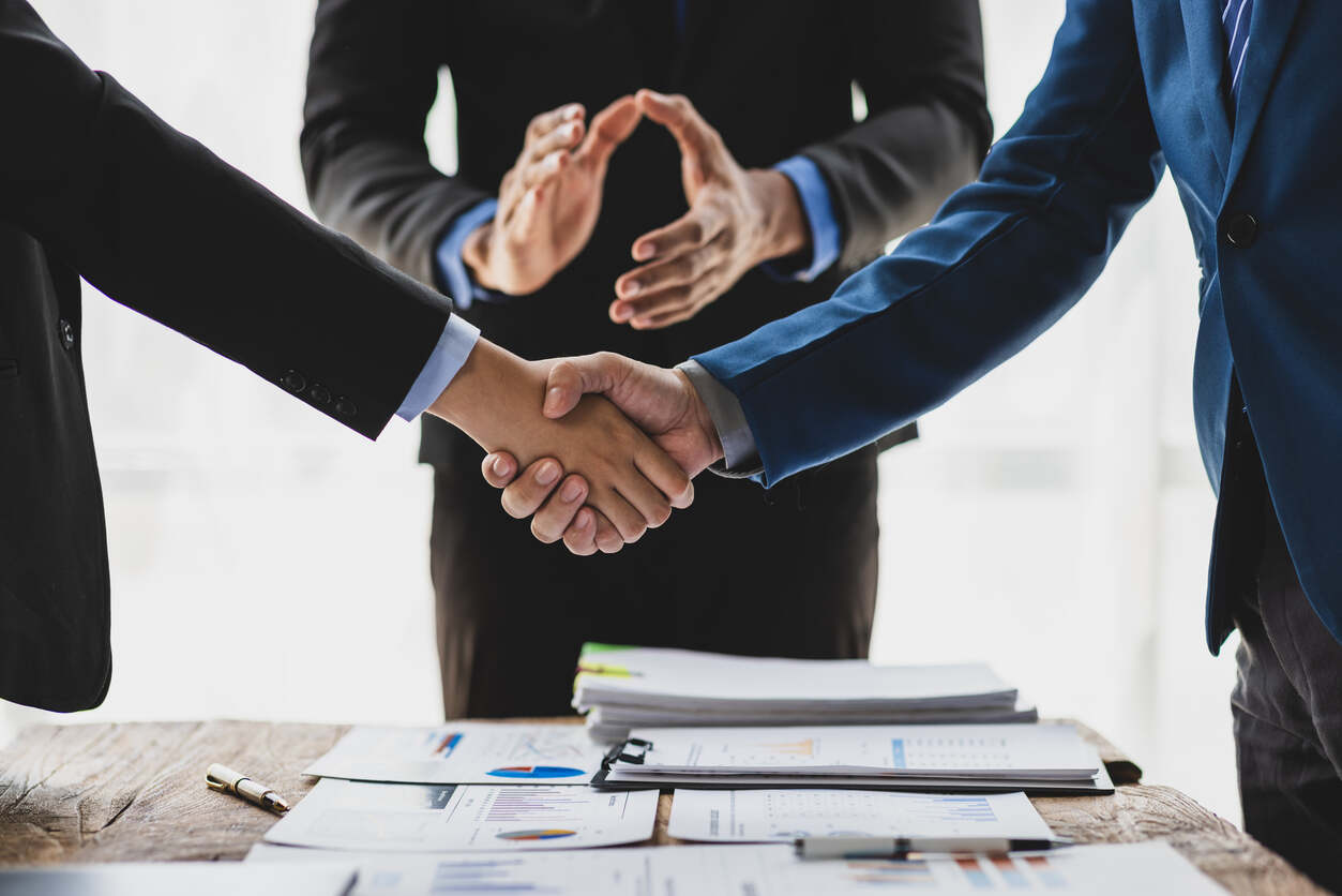Professionals shaking hands over mediation documents, symbolizing pre-suit mediation in Florida.